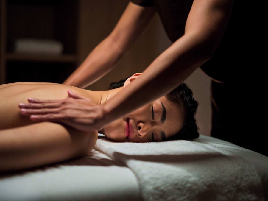 A person receiving a massage on a bed in a dimly lit room.
