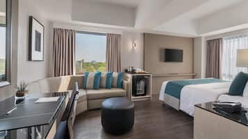 Una habitación de hotel moderna con sofá, cama, escritorio y televisor.