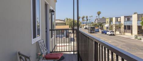 Un balcon donnant sur une rue, avec une balustrade, une table et deux chaises.