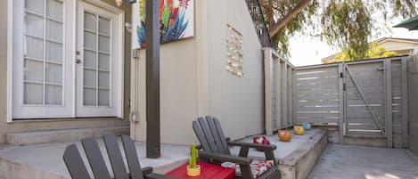 A patio with two Adirondack chairs, a small table, and a potted plant.