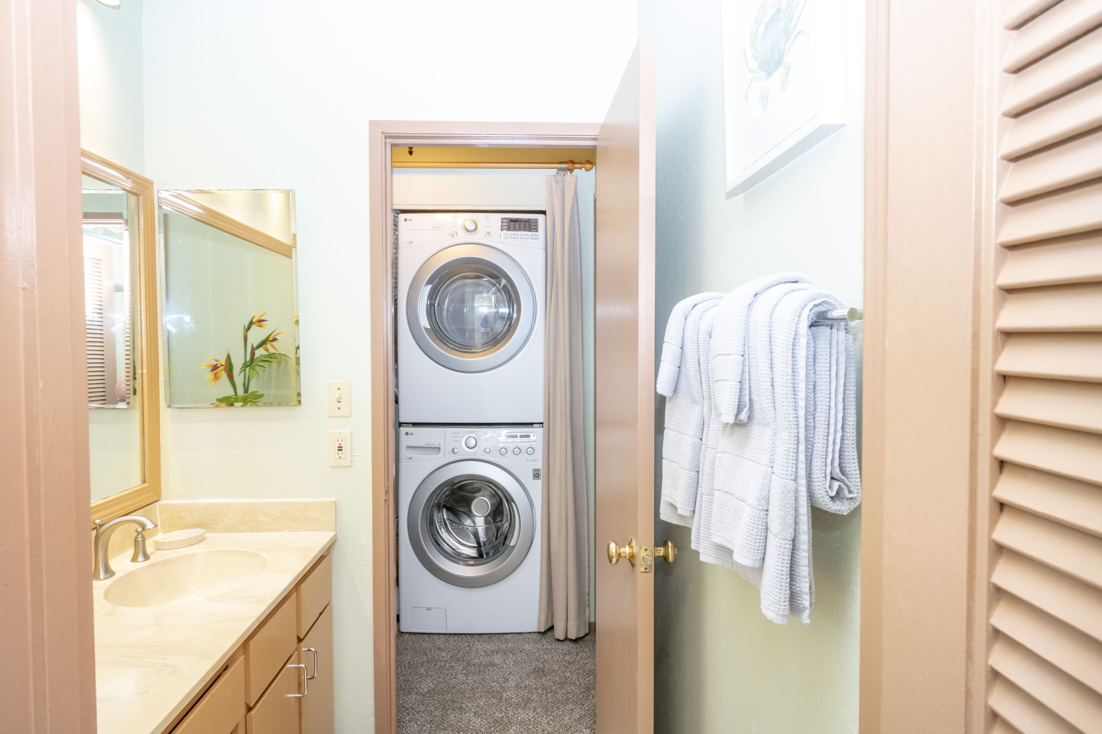 A compact laundry room with a washing machine and dryer, a sink, and a towel rack.
