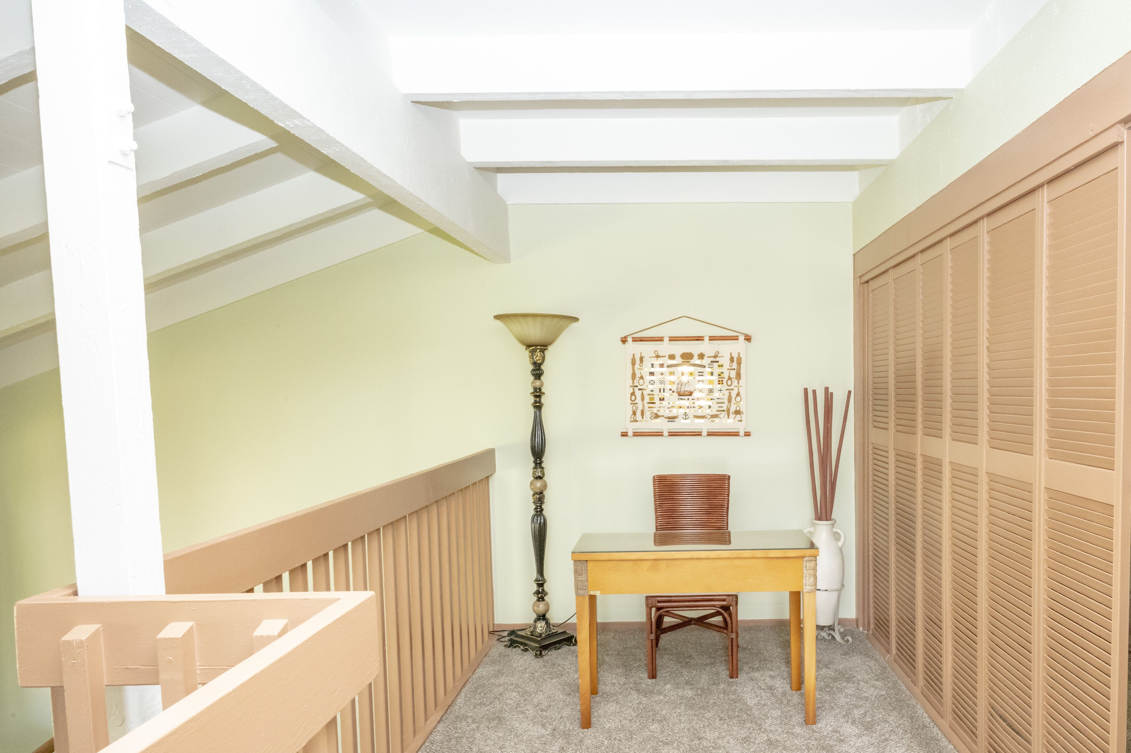 A narrow hallway with a wooden bench, a table, a lamp, and a decorative wall hanging.
