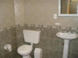 A bathroom with a toilet, sink, and tiled walls. - Hostel Lagares (Mendoza)
