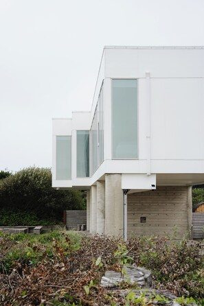 A modern building with large windows and a flat roof. - Cleanline Beach House: Modern Oceanfront Luxury (Cloverdale)