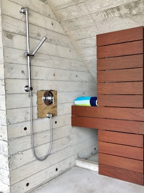 A shower with a metal hose and a wooden panel wall.