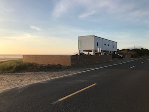 Un edificio moderno con tetto piatto, situato vicino a una spiaggia sotto un cielo sereno.