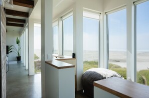 Ein modernes Zimmer mit großen Fenstern, einem Bett, einem Schreibtisch und einer Zimmerpflanze.