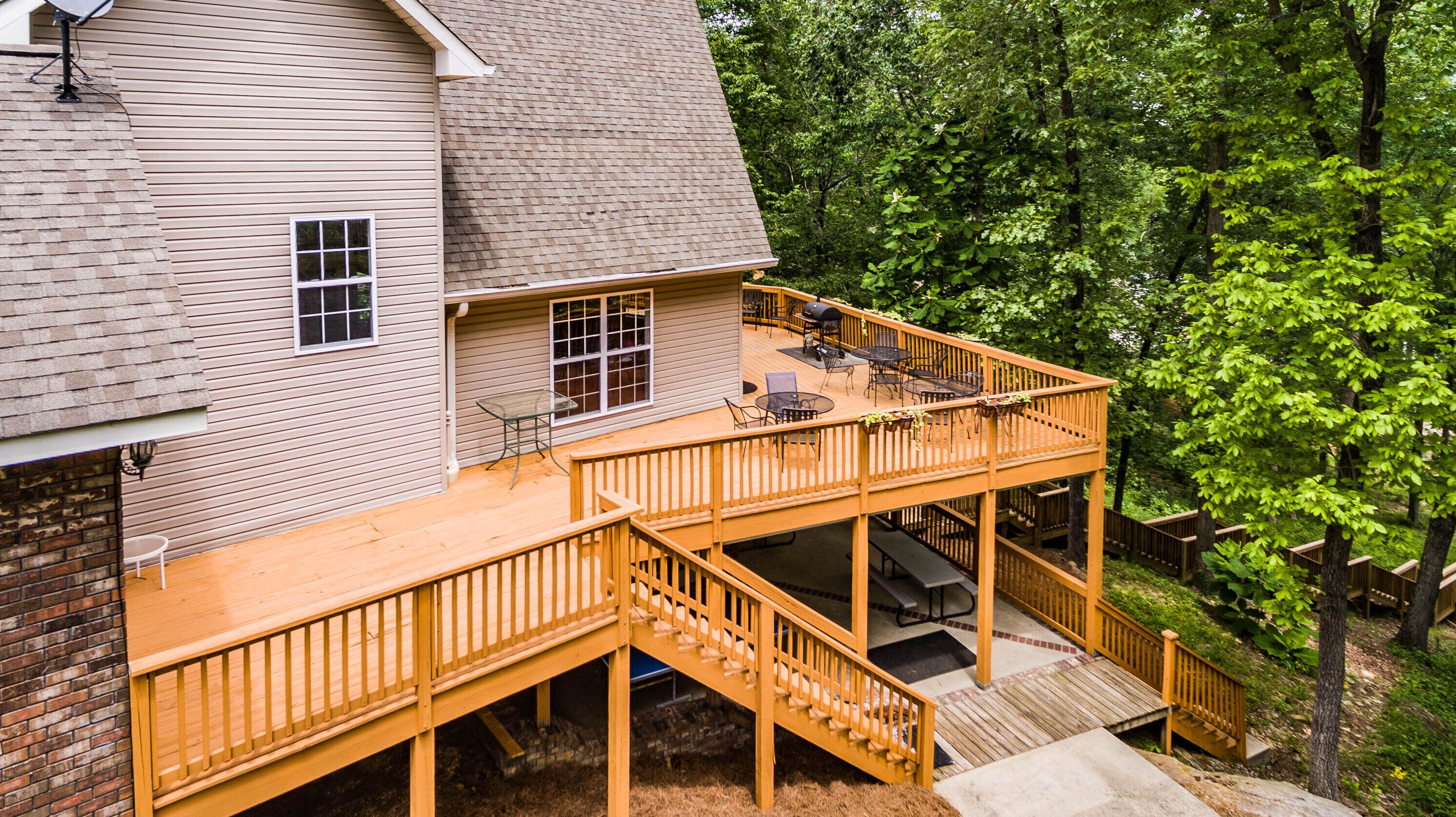 A two-story deck with outdoor furniture and a barbecue grill.