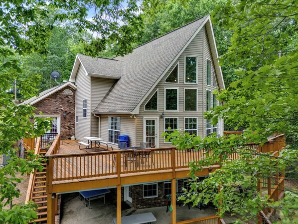 A two-story house with a deck, a brick section, and large windows. - Magnolia Manor: Lakefront, Sleeps 26, Double-Deck Dock, Game Room, Pets OK (Crane Hill)
