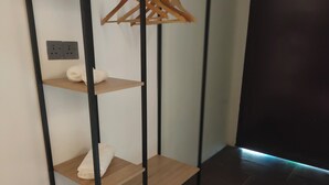 A corner of a room with a wooden shelf unit against a wall, holding a white pillow and folded towels.