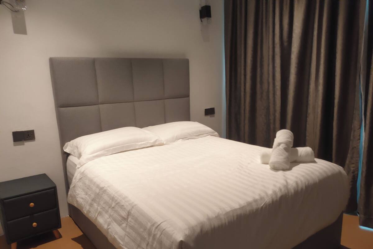 Ein ordentlich bezogenes Bett mit weißen Leinen, einem Kopfteil und einem kleinen Nachttisch mit Schublade.