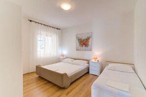 Een slaapkamer met een bed, nachtkastjes, een raam met gordijnen en een schilderij dat aan de muur hangt.