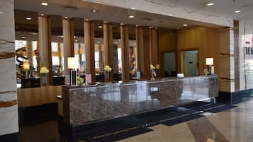 A hotel reception area with a marble counter, American flags, and a modern interior design.