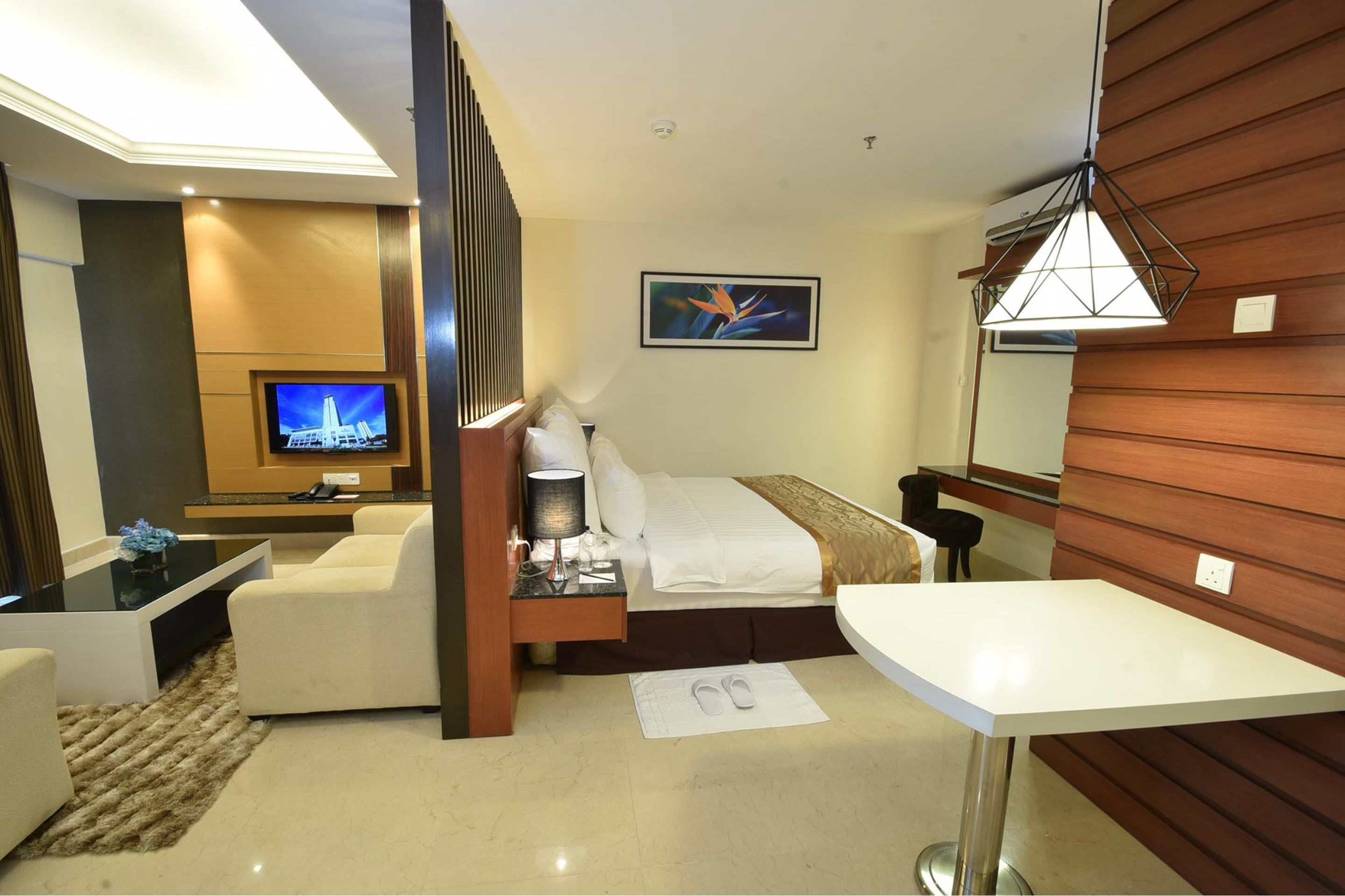 Une chambre d’hôtel avec un lit, un bureau, une télévision, une chaise et une petite table.