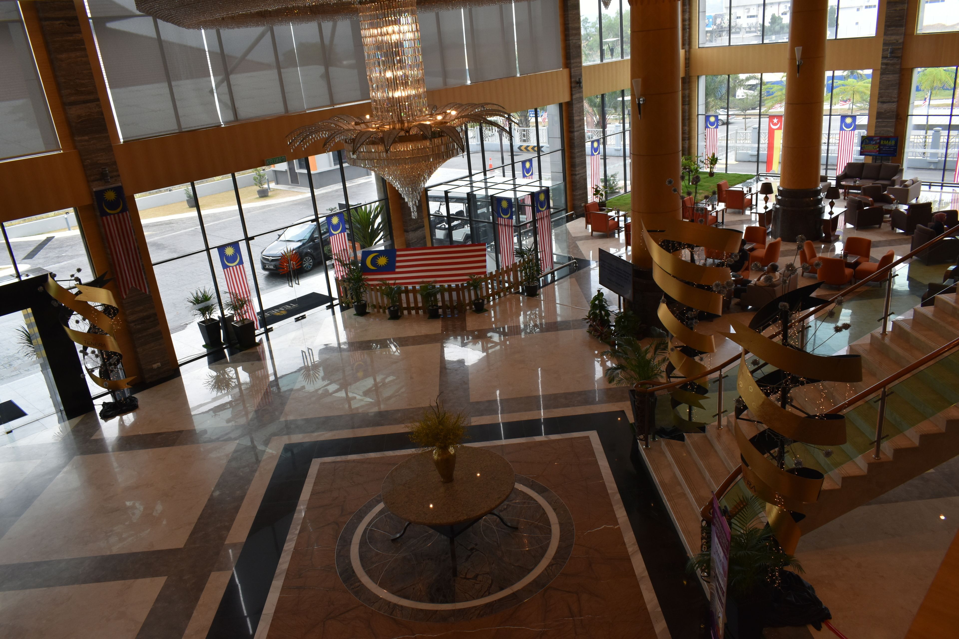 Un vestíbulo amplio con una fuente central, una exhibición de banderas y un área de descanso con una escalera en espiral.