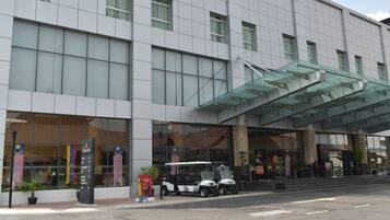 Um hotel moderno com entrada coberta, grandes janelas e exposição de bandeiras.
