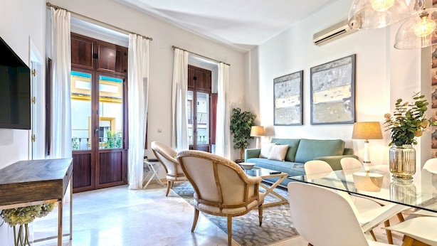 Una sala de estar moderna con una mesa de comedor de vidrio, un sofá y un televisor.