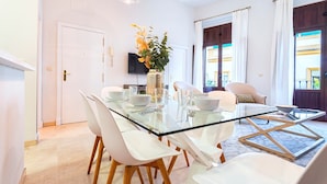 Un comedor moderno con una mesa de vidrio, sillas blancas y un jarrón con flores.
