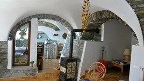 A rustic interior with stone arches, a kitchen area, and a dining space.
