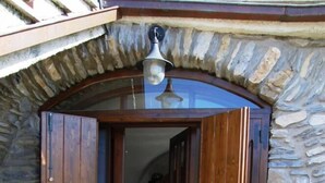 A stone-walled entrance with a wooden door and a hanging light fixture.