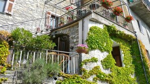 A stone building with a balcony, potted plants, and a small door.
