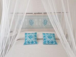 Una cama con dosel blanco y dos almohadas azules.