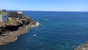 Ein Küstenblick mit Gebäuden auf einem felsigen Klippenhang mit Blick auf das Meer.