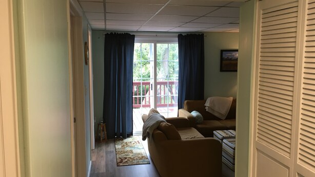 A living room with a sofa, a coffee table, and a view of a deck through a glass door. - Room in Penn State area (State College)