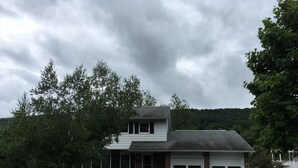 A two-story house with a garage, surrounded by trees and a grassy yard. - Room in Penn State area (State College)