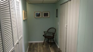 A hallway with a wooden floor, a chair, and two framed pictures on the wall. - Room in Penn State area (State College)