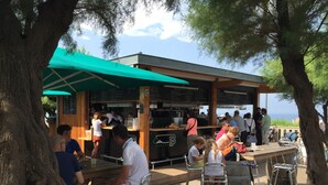 An outdoor café with metal chairs and tables, a green umbrella, and a menu board. - Biarritz, T2 45 m² near Côte des Basques (Biarritz)