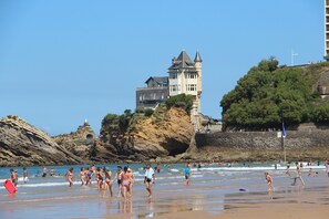 Une plage avec des gens, un château et un phare.