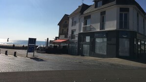 A coastal building with a balcony, a sign for 'bluewave', and a cobblestone street. - Sea view from the large beach (Quiberon)