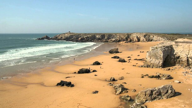 A beach with clear skies, rocky outcrops, and calm waves. - Sea view from the large beach (Quiberon)
