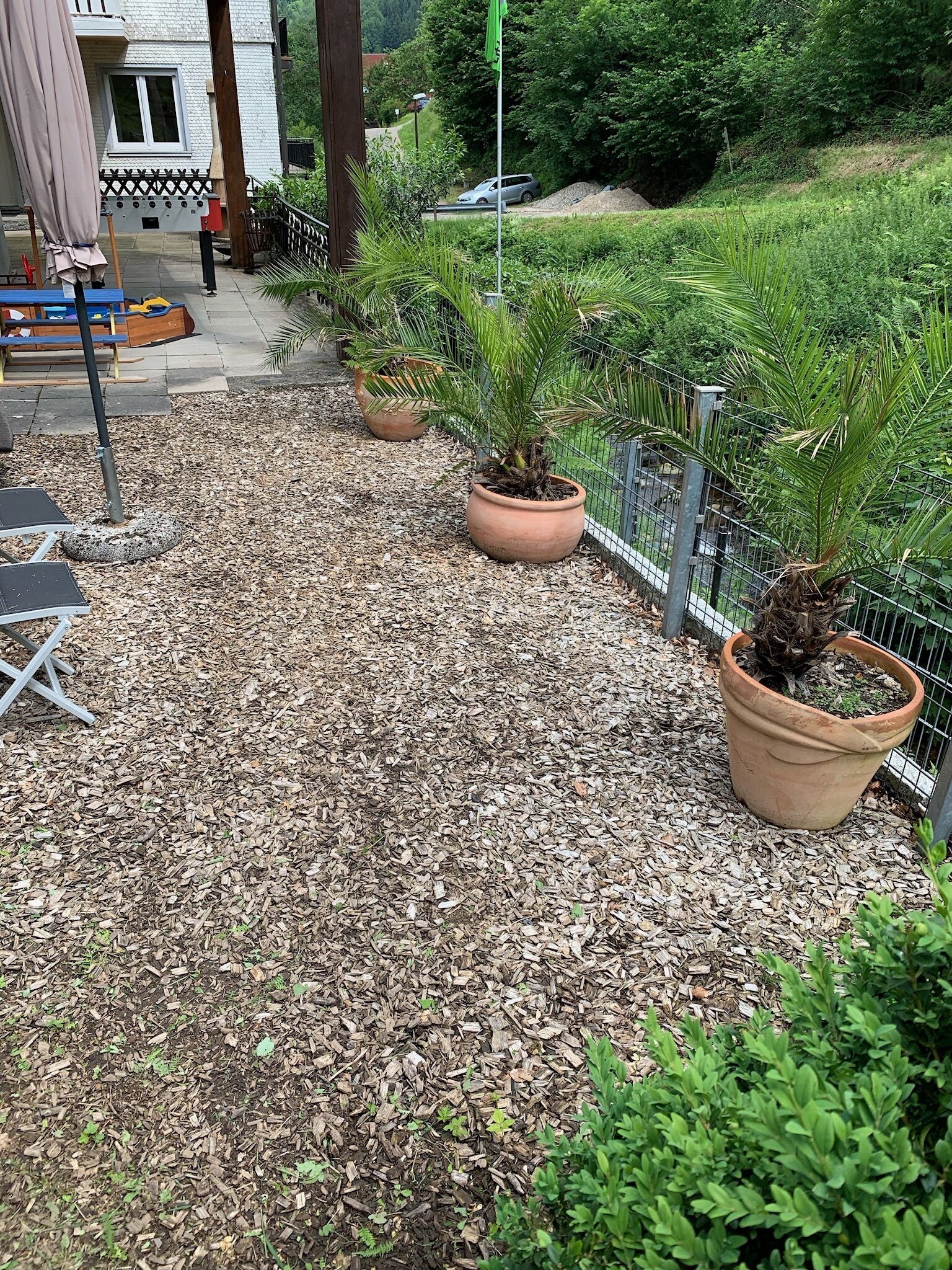 Ein Gartenbereich mit Blumentöpfen, einem Metallzaun und Gartenmöbeln.