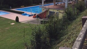 Una piscina con area coperta e un edificio sullo sfondo.