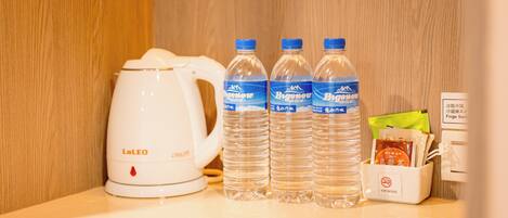 A LaLEO coffee maker, three bottles of Beneo water, and a VIP hotel bag on a counter.