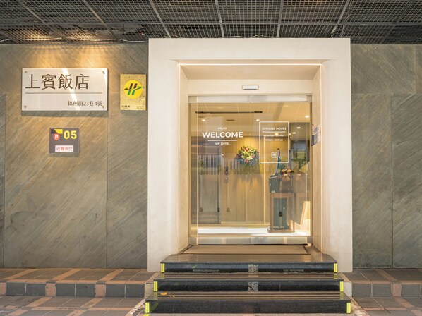 A hotel entrance with a 'WELCOME' sign, a reception desk, and a 'VIP Hotel' sign.