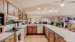 A modern kitchen with wooden cabinets, a central island, and a dining area with chairs. - 29sl - Hot Tub - Sauna - Bbq - Shuffle Board - Sleeps 11 3 Bedroom Home by RedAwning (Deming)