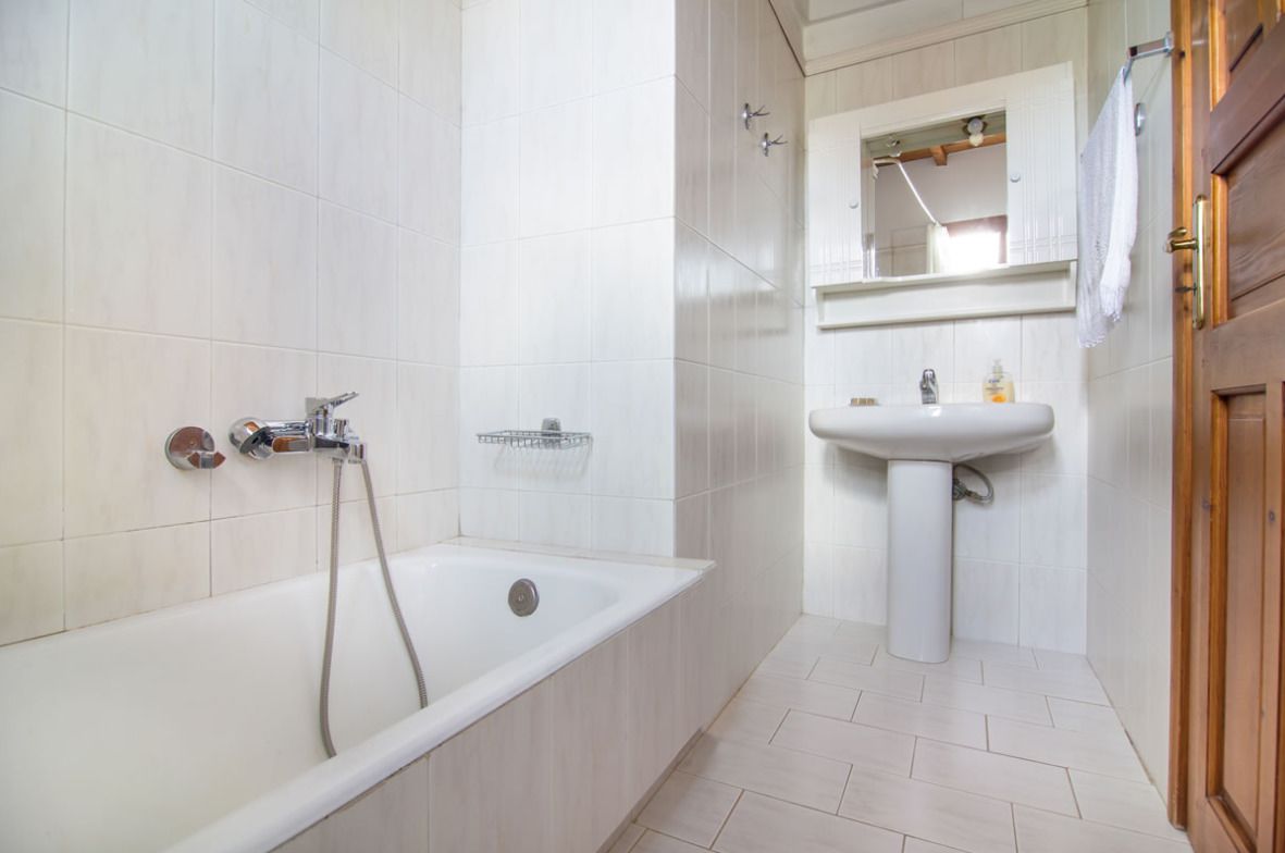 A bathroom with a bathtub, a sink, and a mirror.