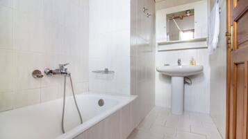 A bathroom with a bathtub, a sink, and a mirror.