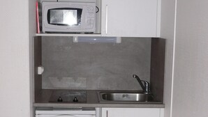 A compact kitchenette with a microwave, sink, and a small refrigerator.