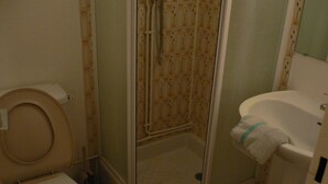 A bathroom with a toilet, a shower enclosure, and a sink.