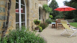 A stone building with large windows, a red umbrella, and outdoor seating. - Beautiful, comfortable property set in unspoilt countryside (La Rouquette)