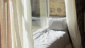 A stone-walled room with a bench and a window with curtains. - Beautiful, comfortable property set in unspoilt countryside (La Rouquette)
