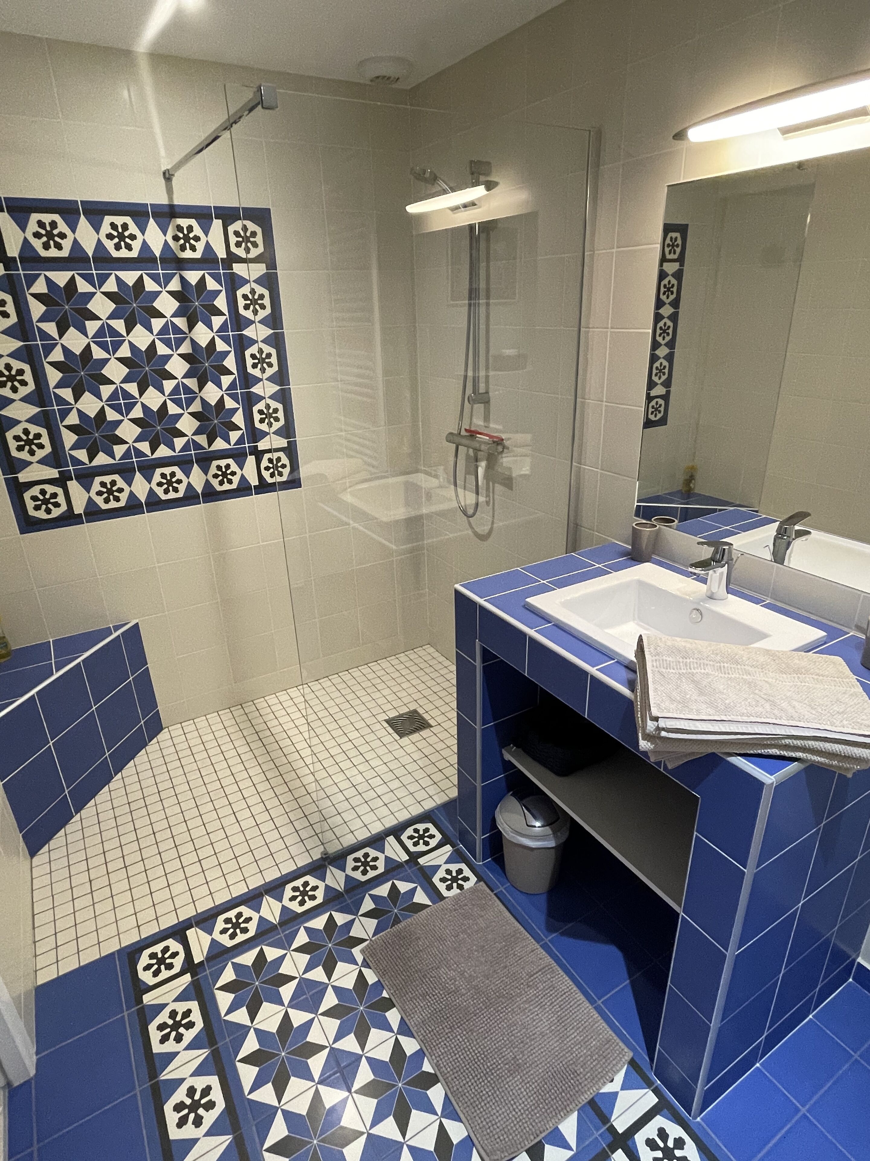 Un baño con ducha, dos lavamanos y un espejo.
