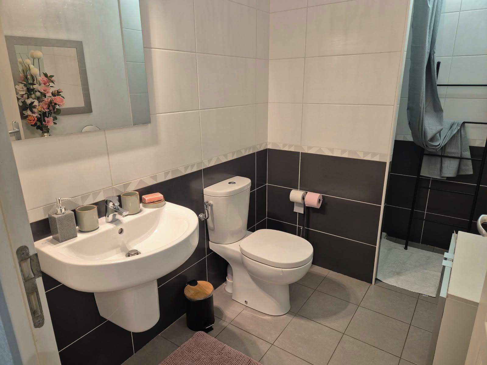 Ein Badezimmer mit einem weißen Waschbecken, einer Toilette und einem Spiegel.