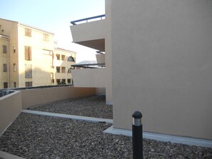 Terraço no telhado com piso de cascalho, paredes bege e um poste preto.