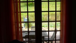 A view through a window with a grid pattern, leading to an outdoor area with a table and chairs.