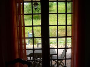 Une vue à travers une fenêtre à carreaux, donnant sur un espace extérieur avec une table et des chaises.
